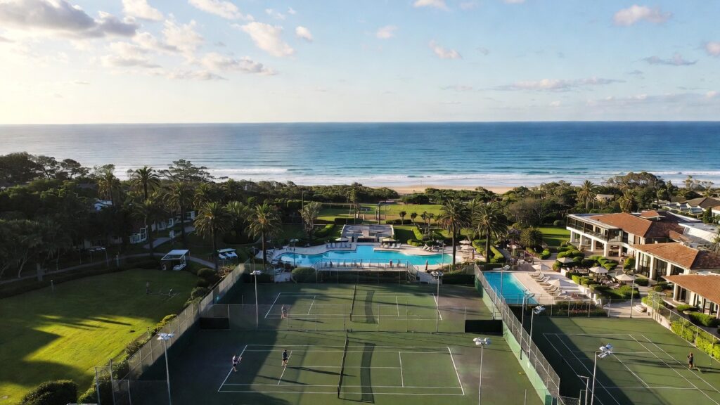 "Aerial view of floodlit hard tennis courts at Crowne Plaza Terrigal Pacific 5 star resort Sydney with tennis courts."