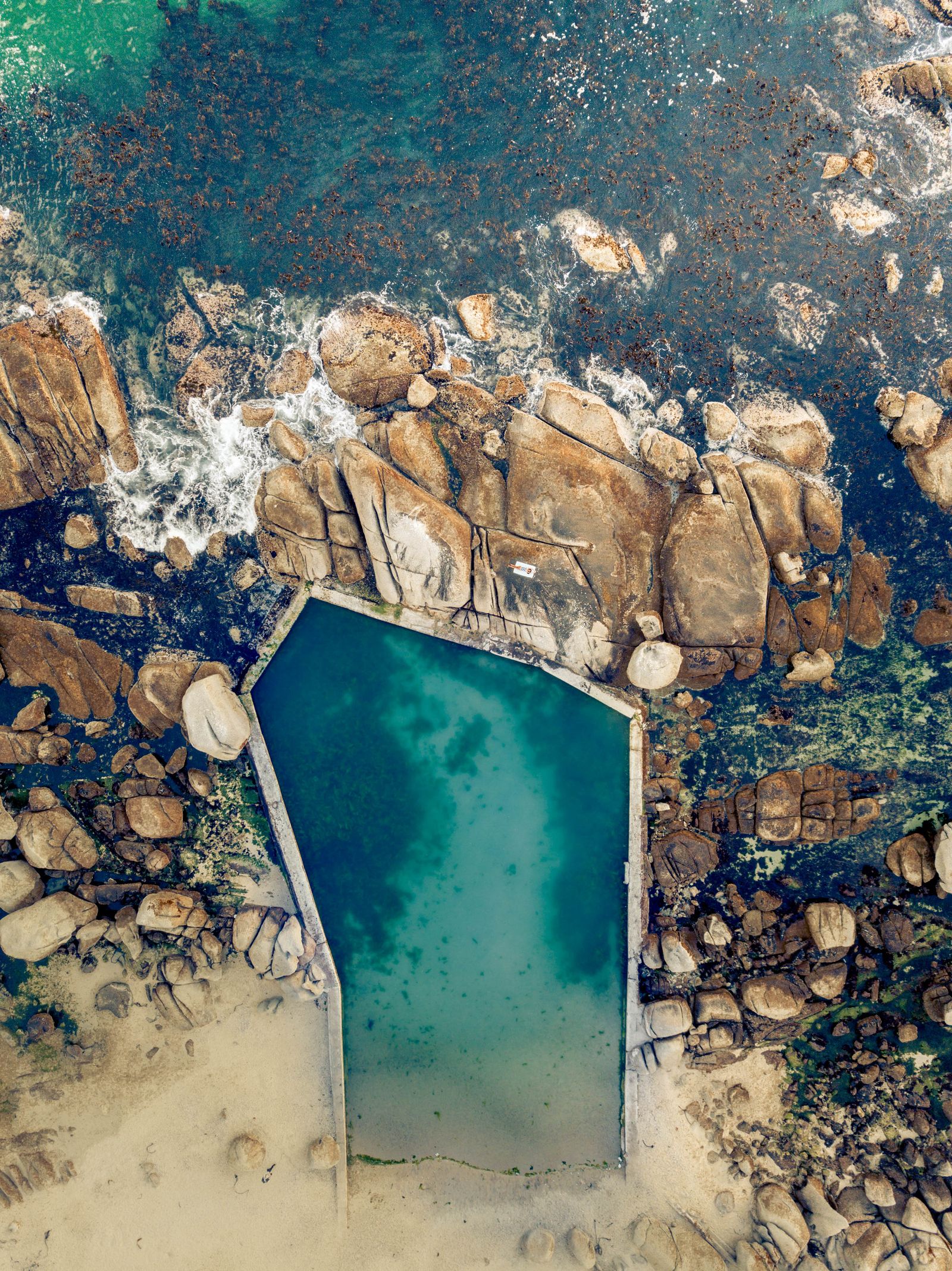 Aerial view of a natural tidal rock pool on a rocky coastline