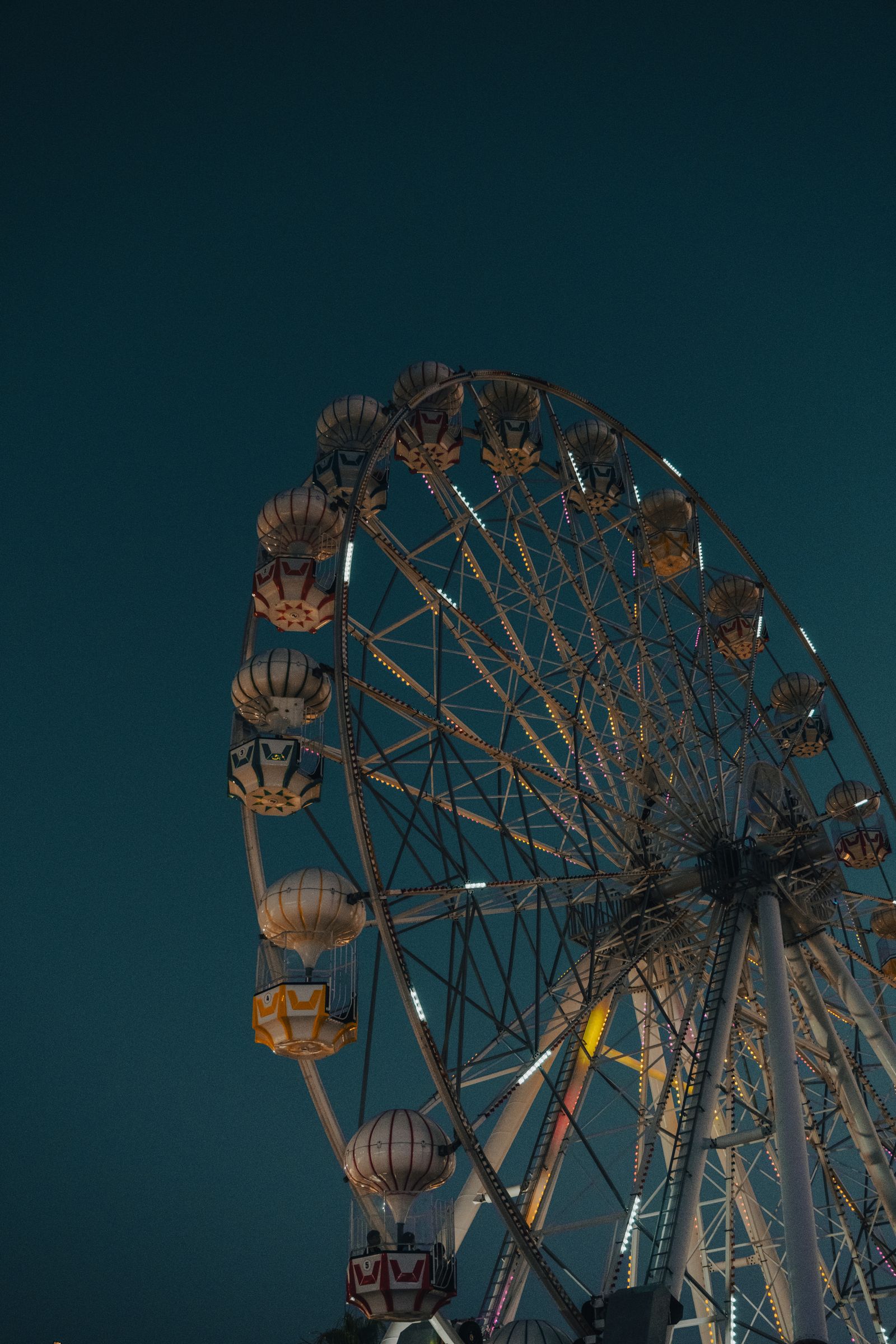 Large illuminated ferris wheel against the night sky at a carnival fairground