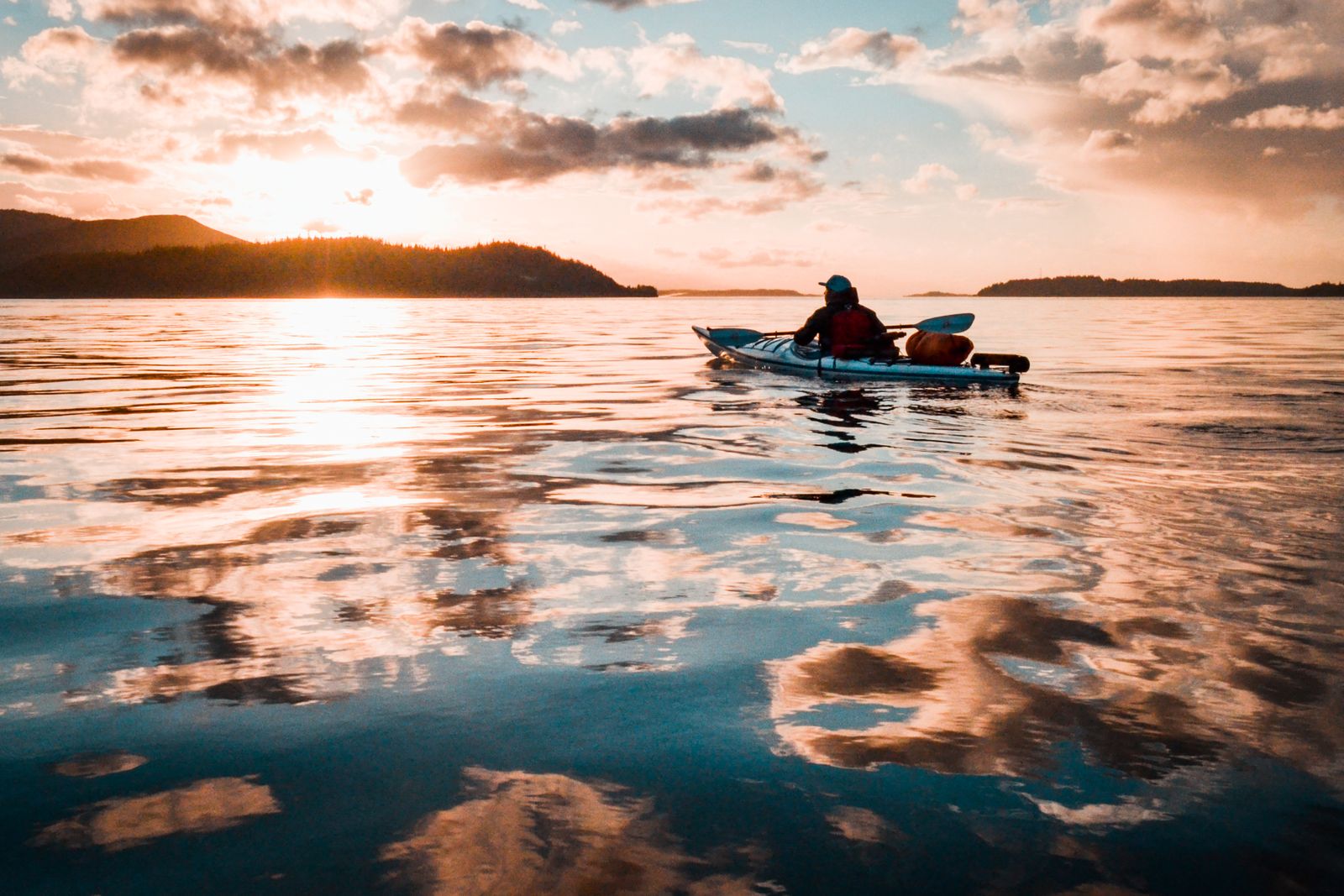 A kayaker paddling on calm water during sunset