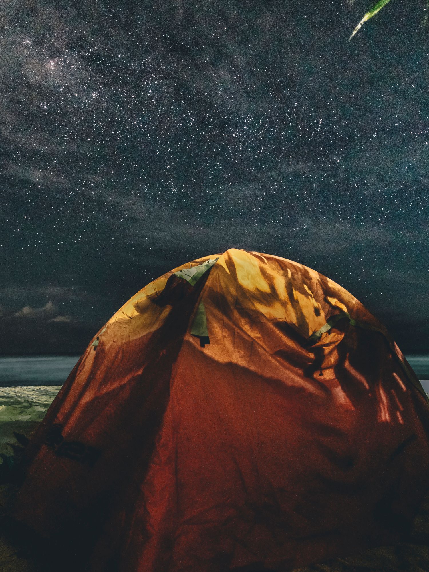 A glowing safari-style tent under a starry night sky